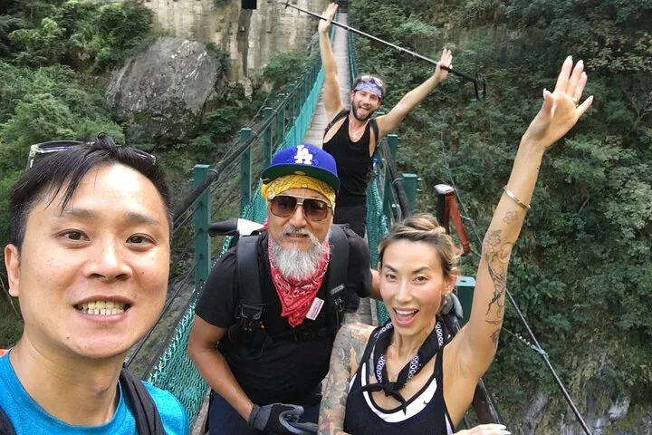 People walking on an elevated wooden boardwalk through a coastal forest.