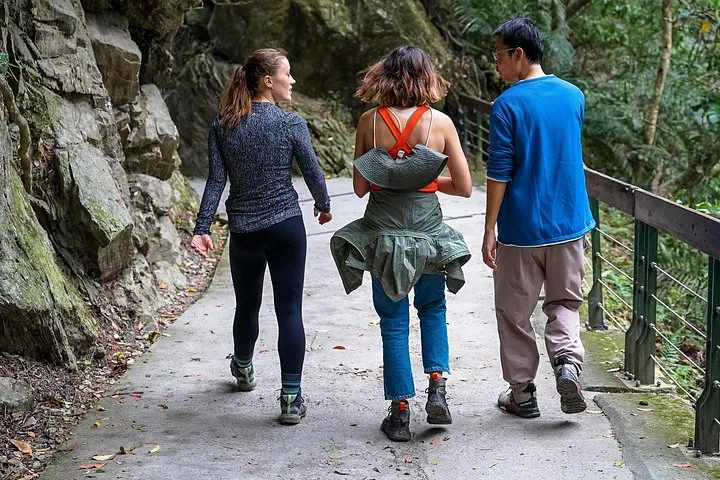 Three people walking away on a paved path along a cliffside in Taroko.