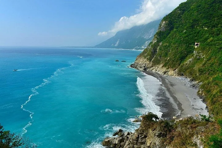 Stunning coastal view of a rocky beach and towering cliffs next to turquoise waters.