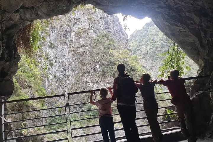 A family looking out from a cave opening over a deep rocky gorge.