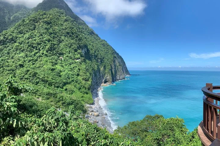 Coastal view from a wooden platform looking at cliffs and blue ocean waters.