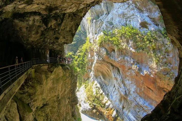 Tourists walking on a narrow pathway carved into the rocky walls of Taroko Gorge.