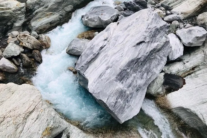 A massive piece of white marble sitting in a fast-flowing turquoise river.